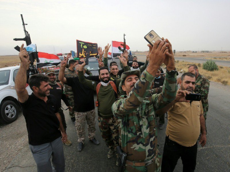 Des membres des forces irakiennes se réjouissent après l'arrivée de convois apportant de la nourriture à Al Qayyarah, près de Mossoul, en Irak, le 28 octobre 2016 - AHMAD AL-RUBAYE [AFP]