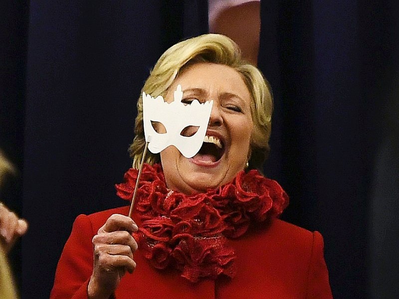 La candidate démocrate à la Maison Blanche Hillary Clinton sourit en portant un masque à bord de son avion pour la campagne électorale, le 31 octobre 2016 à Erlanger, Kentucky - JEWEL SAMAD [AFP]