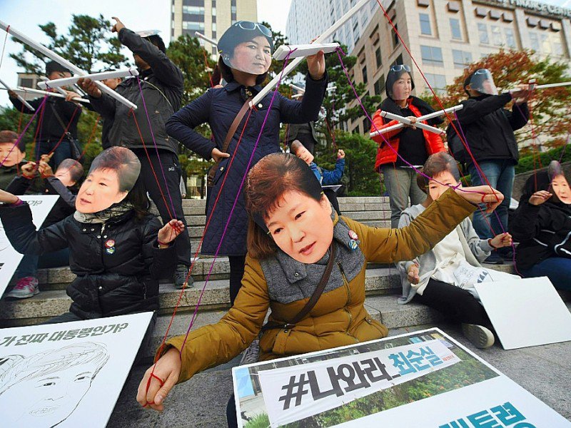 Des manifestants portent des masques à l'effigie de la présidente sud-coréenne Park Geun-Hye et de sa confidente Choi Soon-Sil à Séoul, le 29 octobre 2016 pour dénoncer un scandale de corruption impliquant les deux femmes - JUNG YEON-JE [AFP]