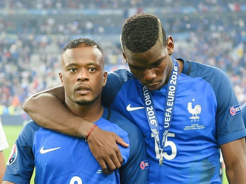 Patrice Evra (g) et Paul Pogba (d) quittent la pelouse du Stade de France dépités après la défaite des Bleus face au Portugal en finale de l'Euro-2016 - PATRIK STOLLARZ [AFP/Archives]