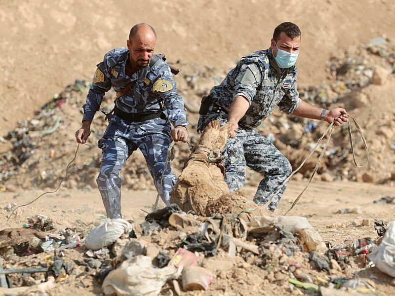 Des soldats irakiens face à un corps tiré d'une fosse commune découverte dans la région de Hamam al-Alil le 7 novembre 2016 près de Mossoul - AHMAD AL-RUBAYE [AFP]