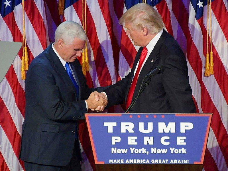 Donald Trump (d) serre la main de son vice président Mike Pence, le 9 novembre 2016 à New York, après avoir été désigné comme le nouveau président américain - JIM WATSON [AFP]