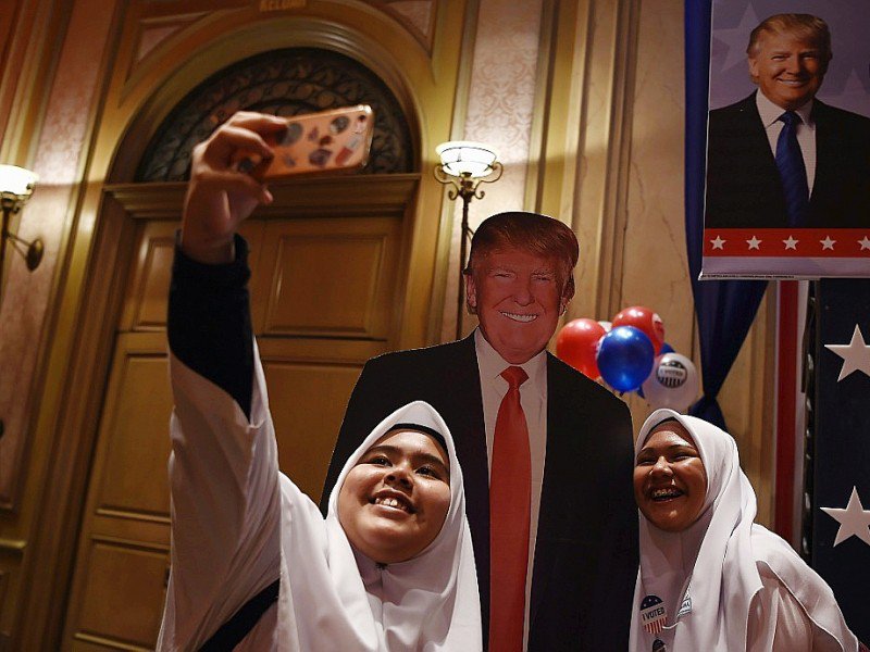 Des écolières malaisiennes posent pour un selfie devant un portrait de Donald Trump, à Kuala Lumpur le 9 novembre 2016 - MANAN VATSYAYANA [AFP]