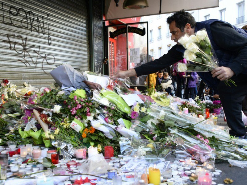 Des fleurs en hommage aux victimes s'amoncellent le 15 novembre 2015 devant le café "La Belle Equipe" à Paris - BERTRAND GUAY [AFP]