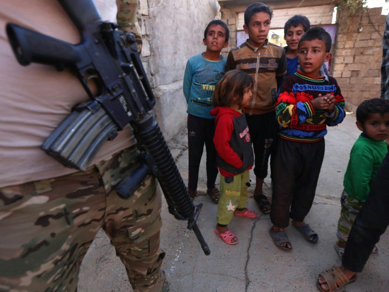 Des enfants près d'un soldat irakien patrouillant dans une rue du village de Jarif, à environ 45 kilomètres au sud de Mossoul, le 12 novembre 2016 - SAFIN HAMED [AFP]