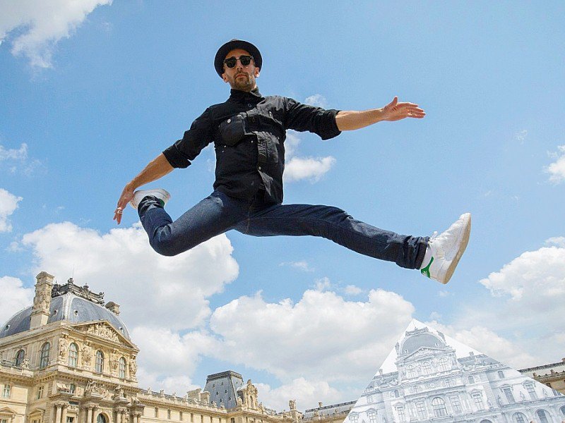L'artiste et photographe français JR saute devant la Pyramide du Louvre à Paris le 25 mai 2016 - JOEL SAGET [AFP/Archives]