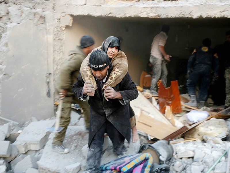 Un habitant d'un des quartiers assiégés d'Alep, extrait une vieille femme, des décombres d'une habitation visée par un bombardement, le 20 novembre - THAER MOHAMMED [AFP/Archives]
