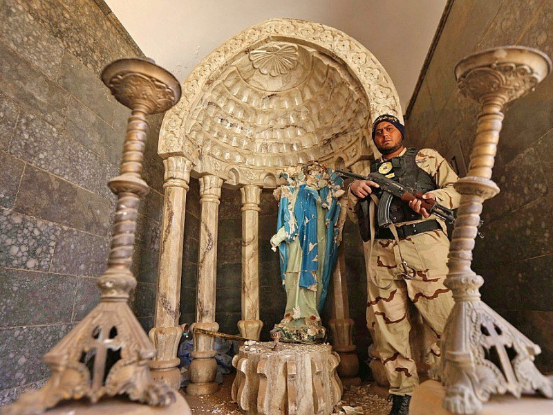 Un soldat des "Brigades de Babylone" près d'une statue de la vierge Marie décapitée par les jihadistes de l'EI, le 22 novembre 2016 à Khidr Ilyas, en Irak - SAFIN HAMED [AFP]