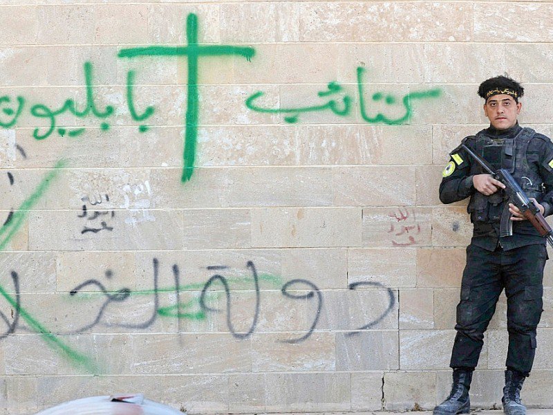 Un soldat des "Brigades de Babylone" se tient près d'un mur du monastère syriaque catholique de Mar Behnam couvert de graffitis laissés par les jihadistes de l'EI, le 22 novembre 2016 à Khidr Ilyas, en Irak - SAFIN HAMED [AFP]