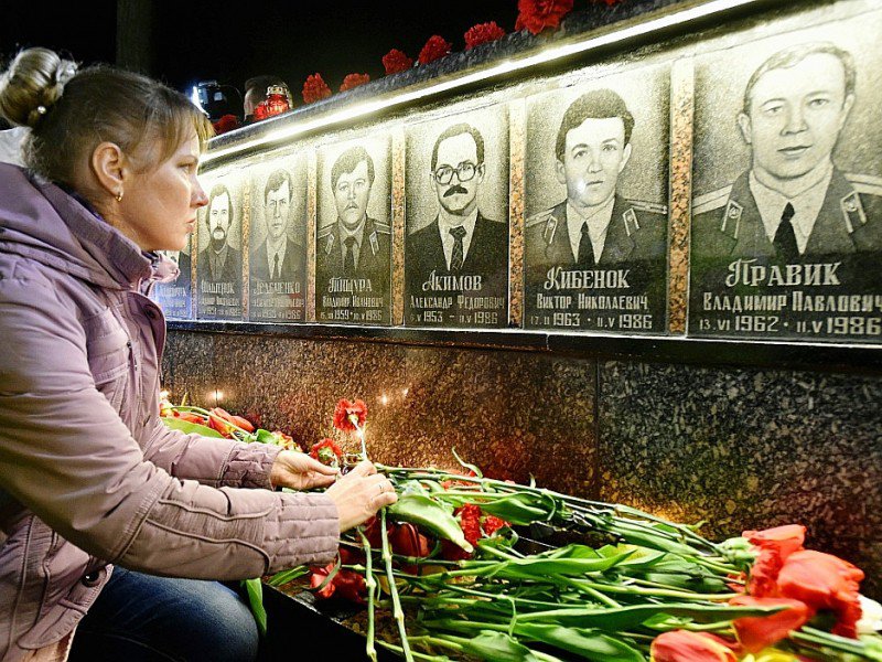 Une femme dépose des fleurs le 26 avril 2016 devant le monument aux victimes de la catastrophe de Tchernobyl, à Slavoutitch, à 50 kms du site accidenté - GENYA SAVILOV [AFP/Archives]