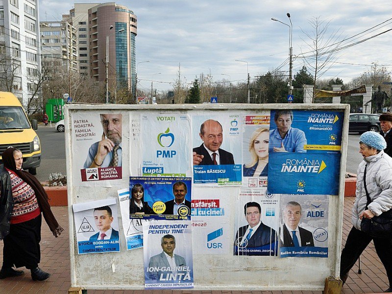 Des Roumains passent devant des panneaux électoraux, le 9 décembre 2016, la veille du scrutin législatif - DANIEL MIHAILESCU [AFP]
