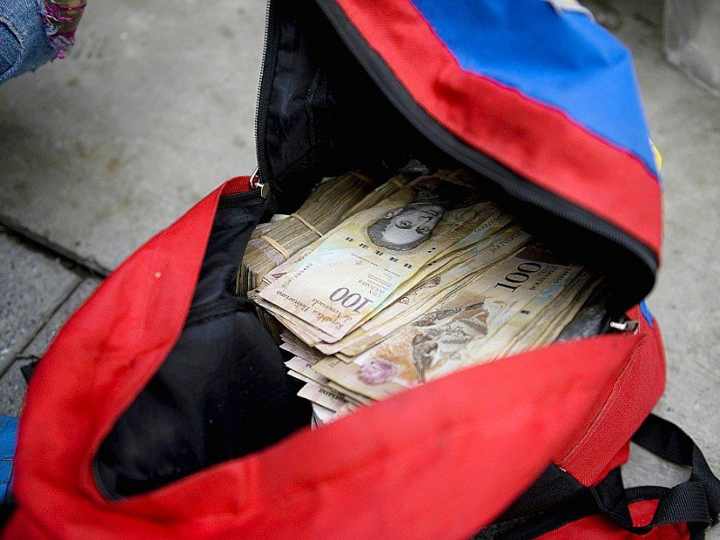 Une femme montre un sac rempli de billets de 100 bolivars qu'elle veut changer à la banque centrale à Caracas, le 16 décembre 2016 - FEDERICO PARRA [AFP]