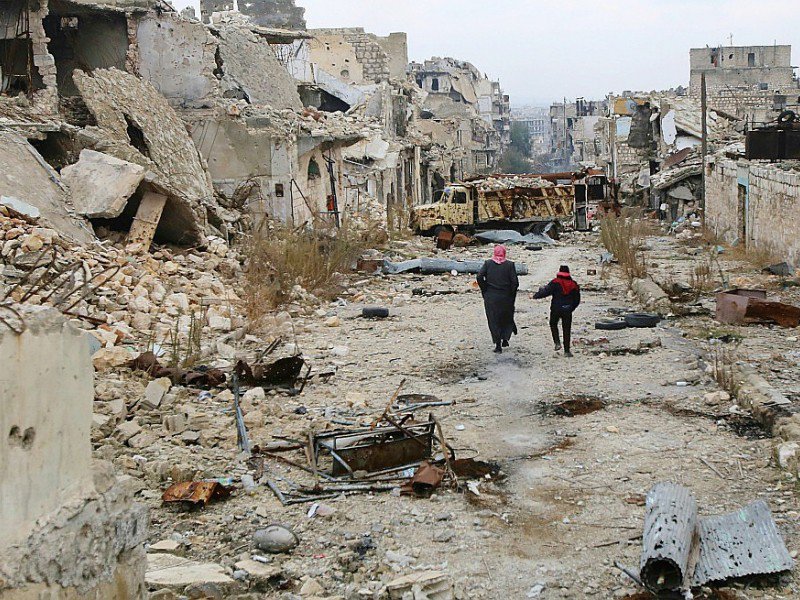Des Syriens marchent au milieu des ruines dans un quartier d'Alep, le 17 décembre 2016 - Youssef KARWASHAN [AFP]