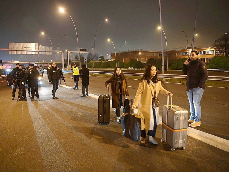 Des voyageurs transportent leurs bagages à pied sur l'autoroute menant à l'aéroport d'Orly bloquée par des chauffeurs VTC le 17 décembre 2016 - CHRISTOPHE ARCHAMBAULT [AFP/Archives]