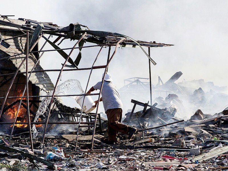 Un homme au milieu des débris calcinés après  l'explosion de feux d'artifice,  le 20 décembre 2016 à Mexico - Israel Gutiérrez R. [AFP]