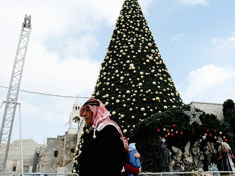 Un Palestinien le 20 décembre 2016 près d'un sapin de Noël géant place de la Mangeoire, à côté de l'Eglise de la Nativité, à Béthléem, lieu de naissance du Christ selon la Bible - MUSA AL SHAER [AFP/Archives]