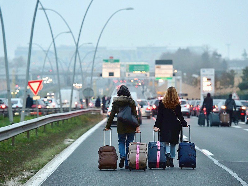 Des voyageurs se rendent à pied à l'aéroport Orly, le 17 décembre 2016 en raison du blocage de l'autoroute par les chauffeurs de VTC - CHRISTOPHE ARCHAMBAULT [AFP]