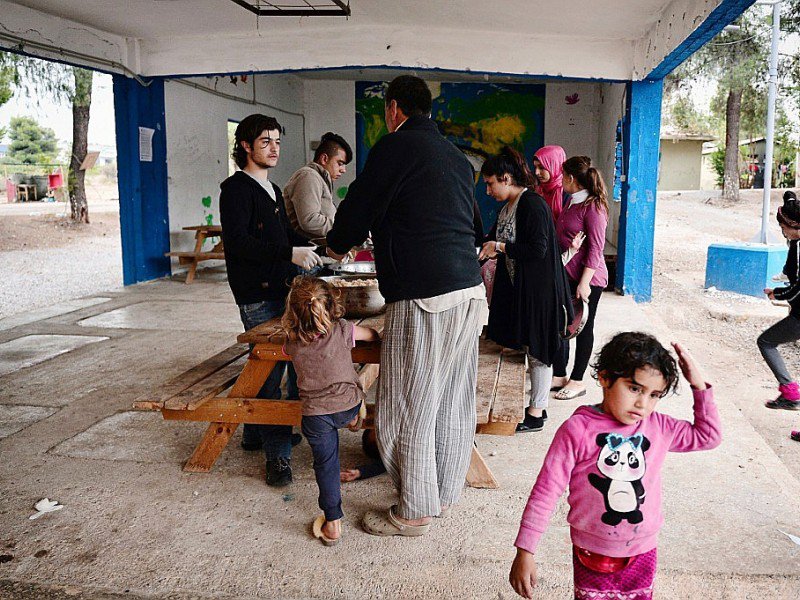 Des réfugiés du camp de Ritsona, au nord d'Athènes, reçoivent un repas préparé par le chef cuisinier syrien Talal Rankoussi, le 21 décembre 2016 en Grèce - LOUISA GOULIAMAKI [AFP]
