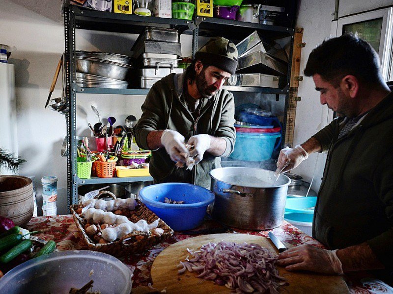 Le chef cuisinier syrien Talal Rankoussi (c) prépare un repas pour les réfugiés du camp de Ritsona, au nord d'Athènes, le 21 décembre 2016 en Grèce - LOUISA GOULIAMAKI [AFP]