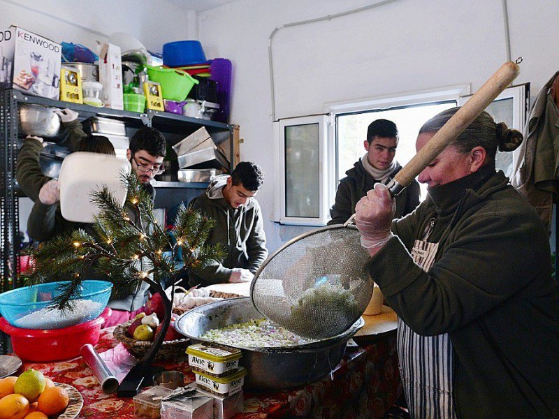 Carolynn Rockafellow (d) et des bénévoles aident le chef cuisinier Talal Rankoussi à préparer un repas pour les réfugiés du camp de Ritsona, au nord d'Athènes, le 21 décembre 2016 en Grèce - LOUISA GOULIAMAKI [AFP]