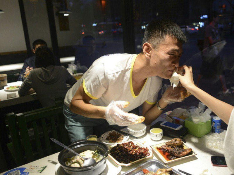 Un homme en train de manger une tête de lapin le 8 septembre 2016 dans un restaurant de Chengdu en Chine - WANG ZHAO [AFP]