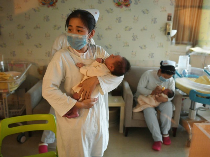 Une infimière chinoise prend soin d'un bébé, au centre Xiyuege à Pékin, le 13 décembre 2016 - Greg Baker [AFP]