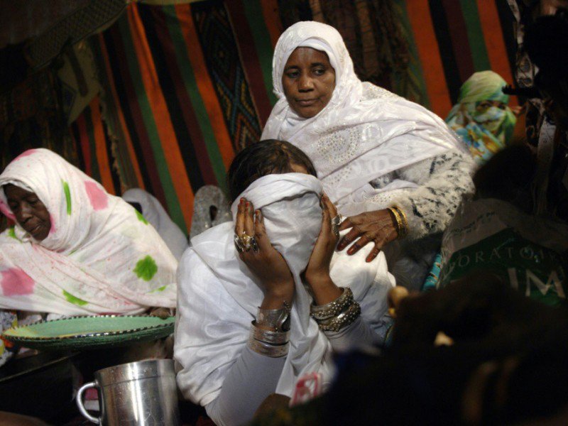 Une jeune femme se voile la face lors d'un mariage collectif le 21 décembre 2016 à Aïn-Salah en Algérie - RYAD KRAMDI [AFP]