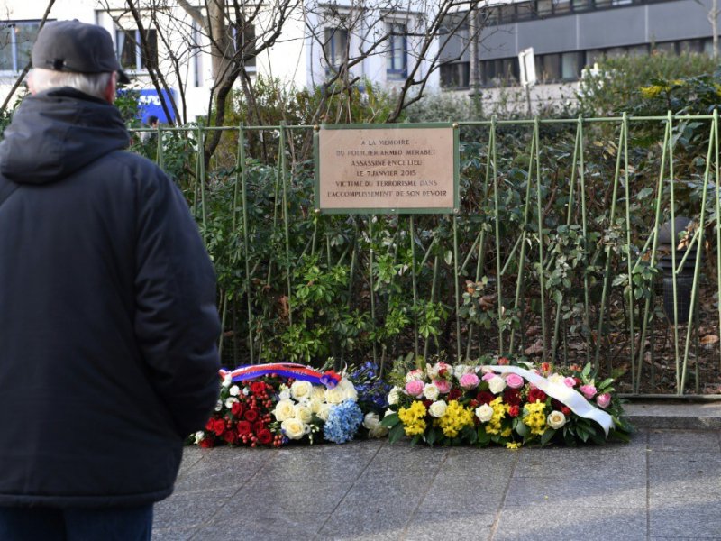 Un homme devant la plaque à la mémoire d'Ahmed Merabet, le 5 janvier 2017 devant Charlie Hebdo à Paris - Eric FEFERBERG [AFP]