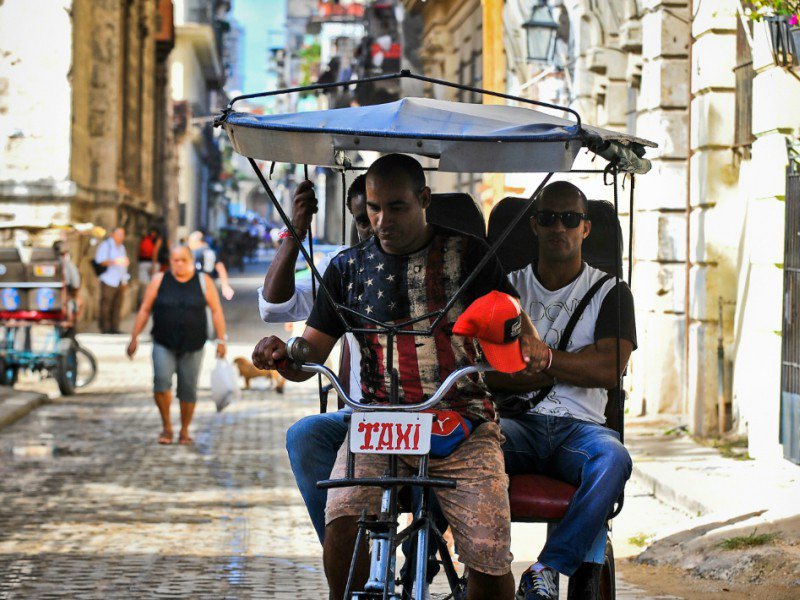 Un Cubain, chauffeur de taxi à trois roues, porte un t-shirt aux couleurs du drapeau américain, le 9 novembre 2016 dans une rue de La Havane - YAMIL LAGE [AFP/Archives]