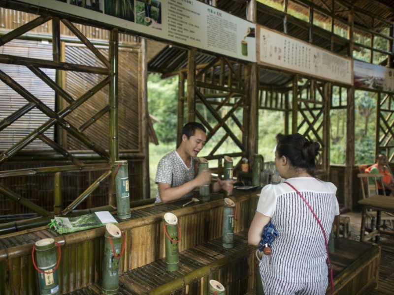 Une touriste achète de l'alcool vieilli dans un tronc de bambou, le 30 juillet 2016 à Vibin - FRED DUFOUR [AFP]