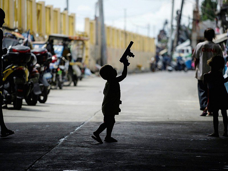 Un enfant joue avec l'arme d'un policier à Manille le 6 octobre 2016 - NOEL CELIS [AFP/Archives]