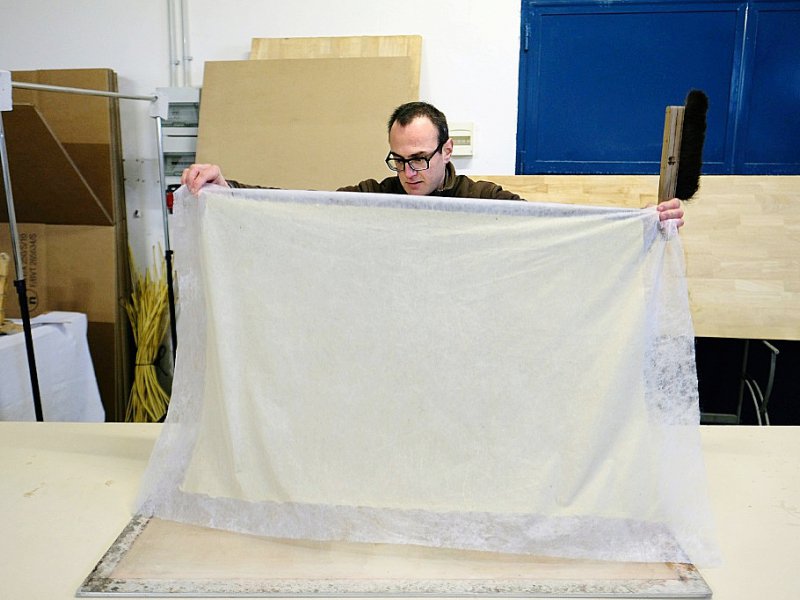 Debout au-dessus d'un bac rempli d'eau et de pâte à papier, Benoît Dudognon secoue un tamis en bambou pour former une feuille. - BORIS HORVAT [AFP]