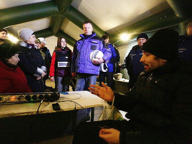 Alexander Hug (C), le premier adjoint en chef de la mission d'observation de l'OSCE en Ukraine, parle avec des habitants de la ville d'Avdiïvka sous une tente dressée pour eux, le 31 janvier 2017 - Aleksey FILIPPOV [AFP]