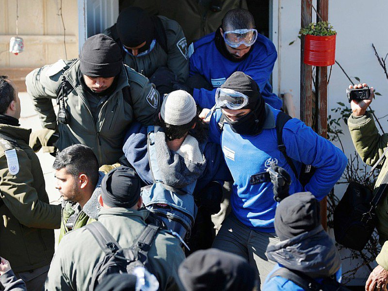 Des policiers israéliens sortent d'un bâtiment un colon qui refuse d'évacuer la colonie d'Amona, le 2 février 2017 en Cisjordanie - Thomas COEX [AFP]