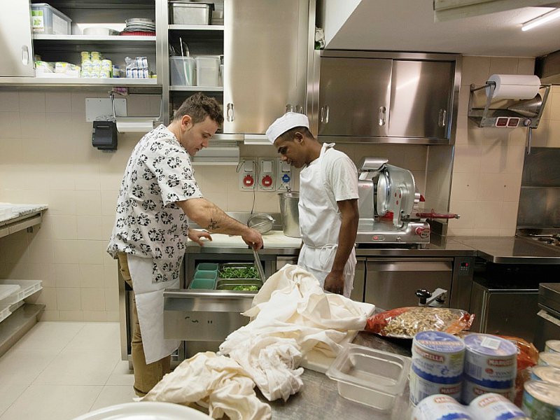 Nazruk Poramanic (à droite), un Bangladais de 21 ans au sourire timide arrivé il y a 18 mois à Lampedusa, vient d'être embauché dans les cuisines d'un restaurant de Bellune. - MIGUEL MEDINA [AFP]