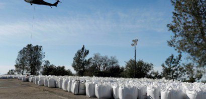 Un hélicoptère dépose d'énormes sacs de pierres pour créer une digue d'urgence et boucher les trous le 14 février 2017 à Oroville - MONICA DAVEY [AFP]