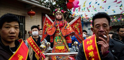Des enfants, maquillés et habillés de costumes bordés et colorés, en parade, debout sur des palanquins, dans les rues de Tufang, le 11 février 2017 dans l'est de la Chine - Johannes EISELE [AFP]
