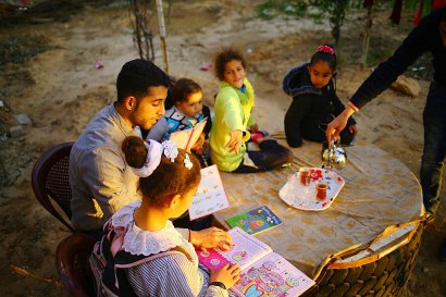 Mosaab Abou Toha (G) lit des livres à des enfants dans le jardin d'une maison de Beit Lahya dans le nord de Gaza le 20 février 2017 - MOHAMMED ABED [AFP]