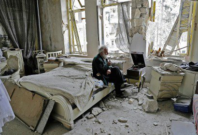Mohamed Mohiedine Anis, 70 ans, fume la pipe et écoute de la musique sur son gramophone dans sa chambre à coucher détruite par des bombardements, le 9 mars 2017 à Alep dans le quartier autrefois rebelle de Chaar - JOSEPH EID [AFP]