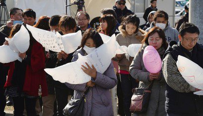 Des Japonais se recueillent avant un lâcher de ballons le 11 mars 2017 à Natori - KAZUHIRO NOGI [AFP]