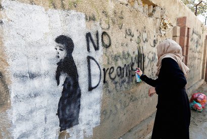 "Pas de rêves", a tracé à la peinture noire sur un pan de mur une jeune artiste, avant de s'assoir au sol sous une fresque représentant trois soldats lourdement armés. - Mohammed HUWAIS [AFP]