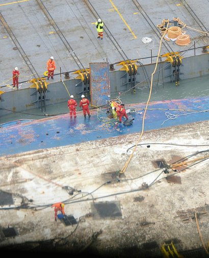 Des ouvriers sur un morceau de la coque du Ferry Sewol lors des opérations de renflouage, le 23 mars 2017 à Jindo - Handout [HANKOOK ILBO/AFP]