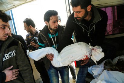 Des Syriens transportent le corps d'un enfant tué lors d'une frappe aérienne à Hamouria près de Damas au cours de laquelle au moins 16 civils sont morts et des dizaines de personnes ont été blessées, le 25 mars 2017 - AMER ALMOHIBANY [AFP]
