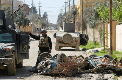 Un membre des forces de la coalition près d'un char détruit  lors d'un raid visant le groupe EI le 26 mars 2017 dans le quartier al-Jadida à Mossoul - AHMAD AL-RUBAYE [AFP]