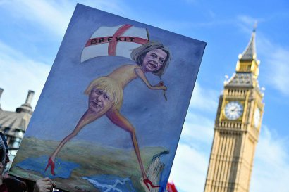 Des manifestants brandissent une pancarte à l'effigie de Theresa May et du ministre britannique des Affaires étrangères Boris Johnson à Londres lors d'une manifestation anti-Brexit, le 25 mars 2017,  à deux jours de son déclenchement - Chris J Ratcliffe [AFP]