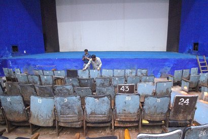 Un spectateur cherche sa place parmi les chaises en fer du cinéma Regal, l'un des plus anciens d'Inde, le 27 mars à New Delhi, trois jours avant sa fermeture - Dominique FAGET [AFP]