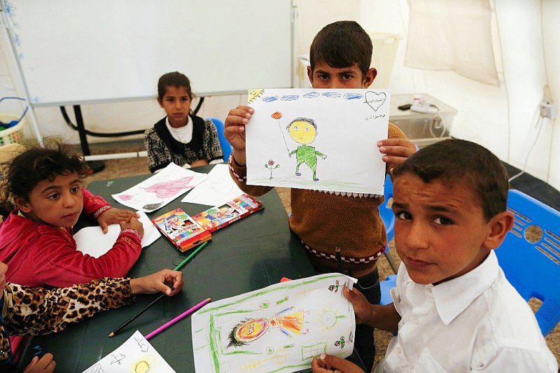 Des enfants irakiens qui ont fui les combats à Mossoul montrent les dessins qu'ils ont faits au camp de Hasan Sham situé à 30 km à l'est de Mossoul, le 31 mars 2017 - AHMAD GHARABLI [AFP]