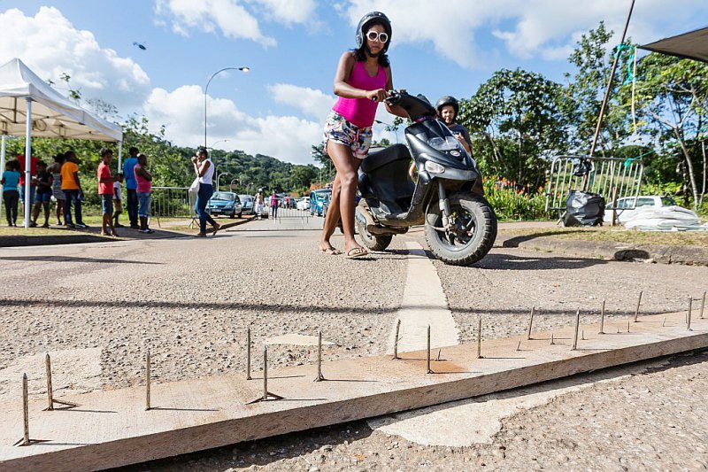 Une femme pousse son scooter devant des pointes bloquant une route vers l'aéroport le 29 mars 2017 à Cayenne, en Guyane - jody amiet [AFP/Archives]