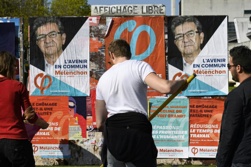Des militants de "La France Insoumise" collent des affiches de leur candidat, Jean-Luc Mélenchon, le 7 avril à Rennes - DAMIEN MEYER [AFP]