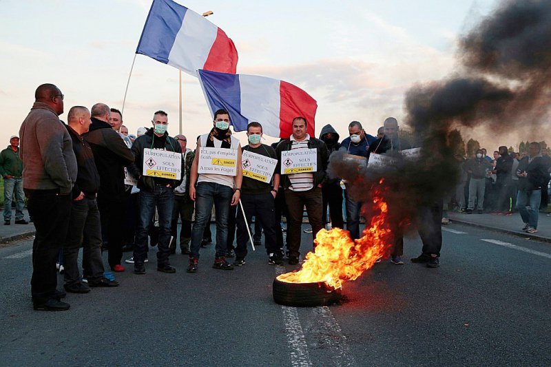 Des manifestants brandissent des pancartes et le drapeau français devant un pneu brûlé à la prison de Fleury-Mérogis, dans l'Essonne, près de Paris, le 10 avril 2017 - GEOFFROY VAN DER HASSELT [AFP]